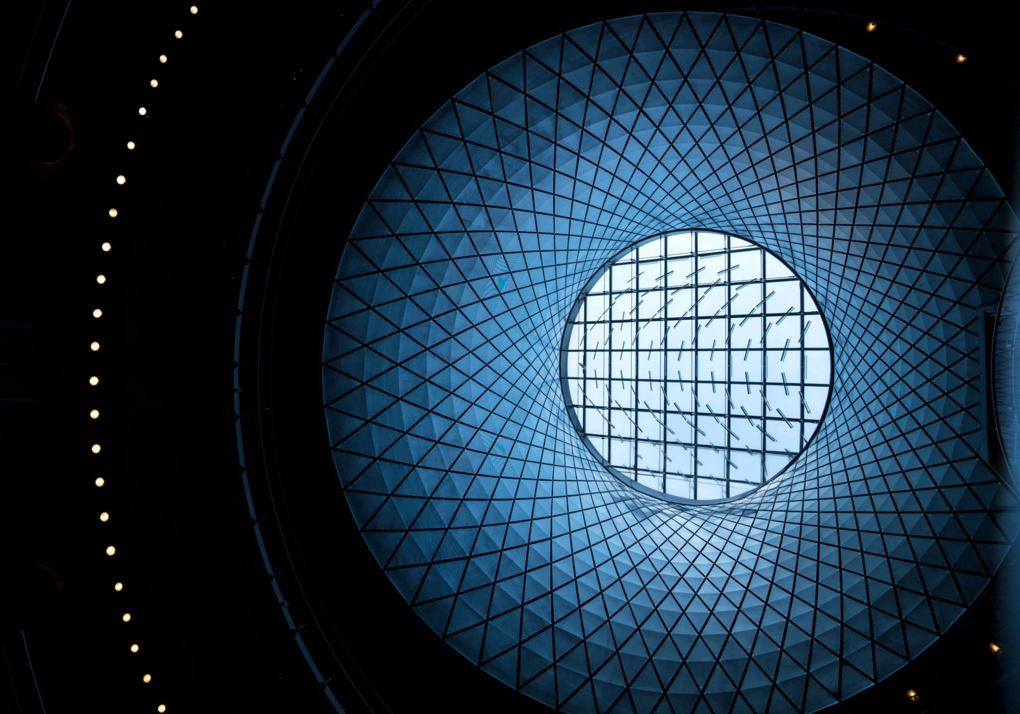 Modern Glass Architecture Low angle view Kreisförmige blaue Struktur mit hellem Mittelpunkt symbolisiert fokussierte Executive Search bei Heinrich & Coll.