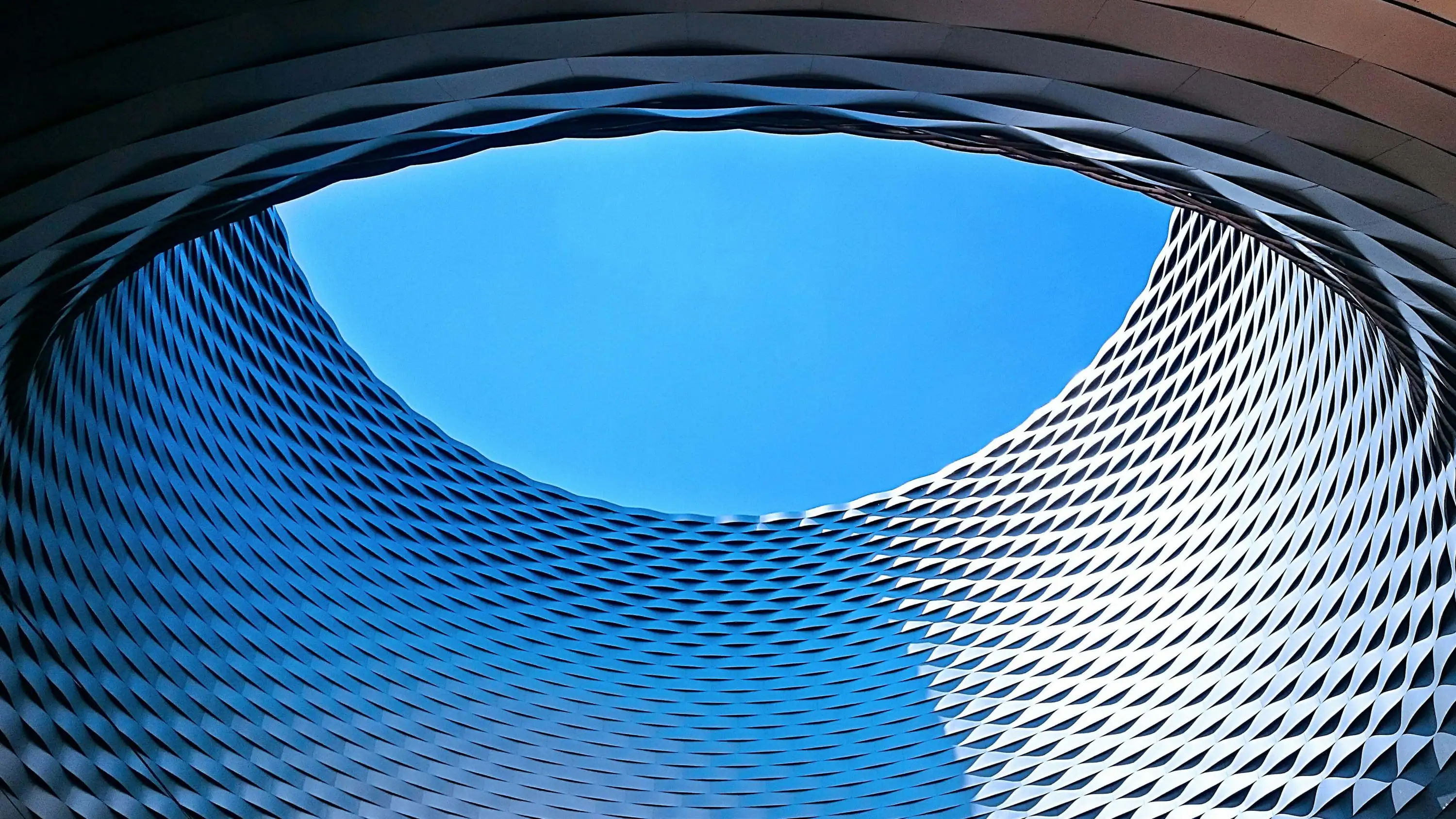 Runde Fassade mit Metallstrutur die zum Himmel geöffnet ist, symbolisiert Offenheit im Bereich Executive Search bei Heinrich & Coll.