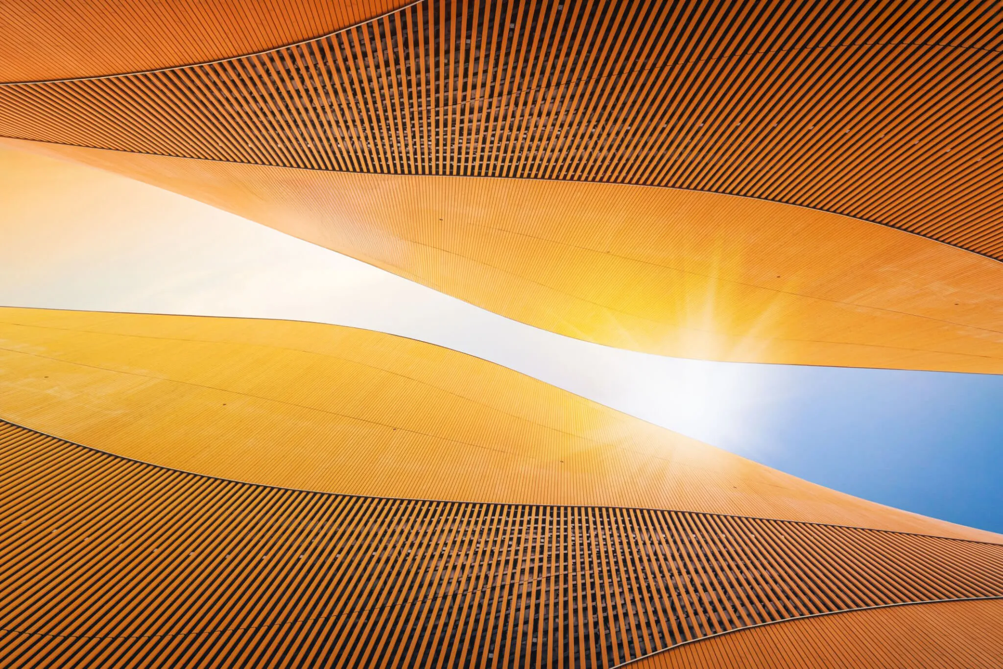 Abstract modern architecture detail with copy space. Sky and sunshine. Upward view from the ground. Abstrakte orange Wellenstruktur symbolisiert Innovation und kreative Lösungen bei Heinrich & Coll.